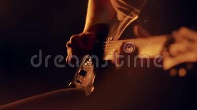 人类的手在电吉他上演奏。 在舞台上演奏吉他的摇滚乐手，在风景优美的灯光下